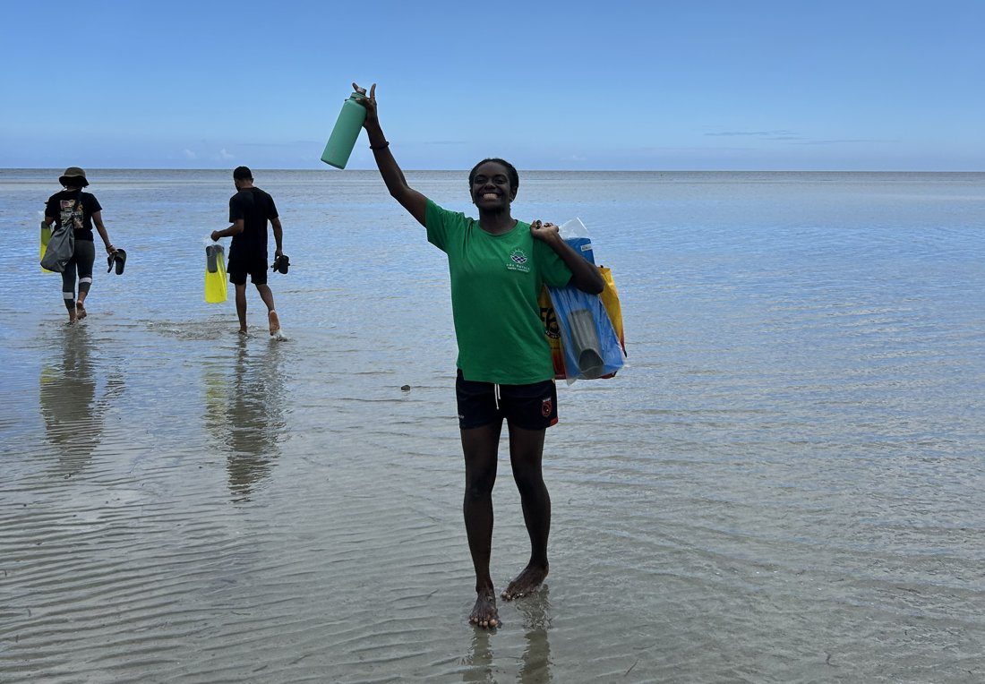 An Eda Davara team member waving from the Kohua flats as teammates carry survey gear