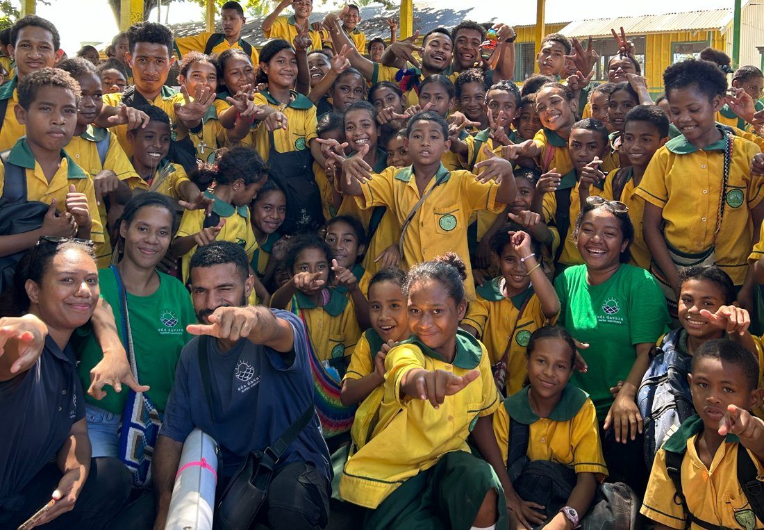 Students in yellow and green school uniforms cheering with the Eda Davara team