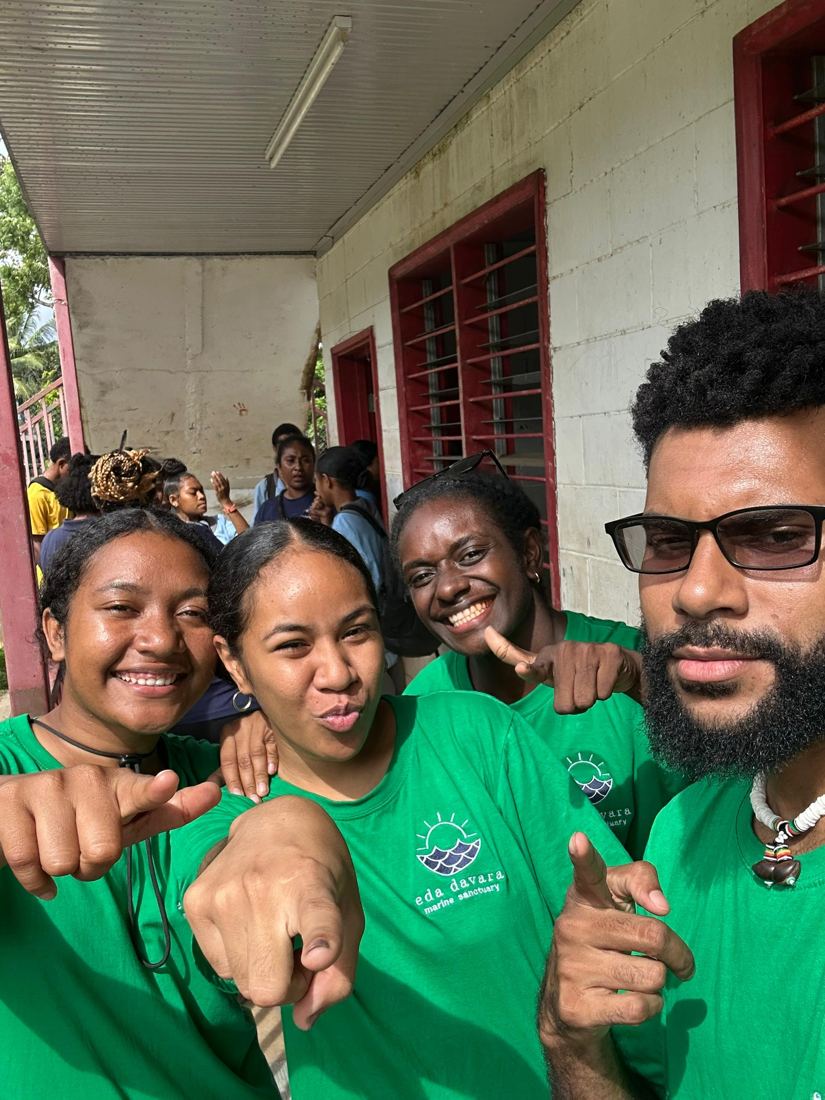 Four EcoScholars in green Eda Davara shirts smiling at a school